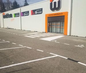 Marquage au sol chantier Weldom Lavelanet avec places de parking, pi&eacute;tonnier et places PMR devant le magasin